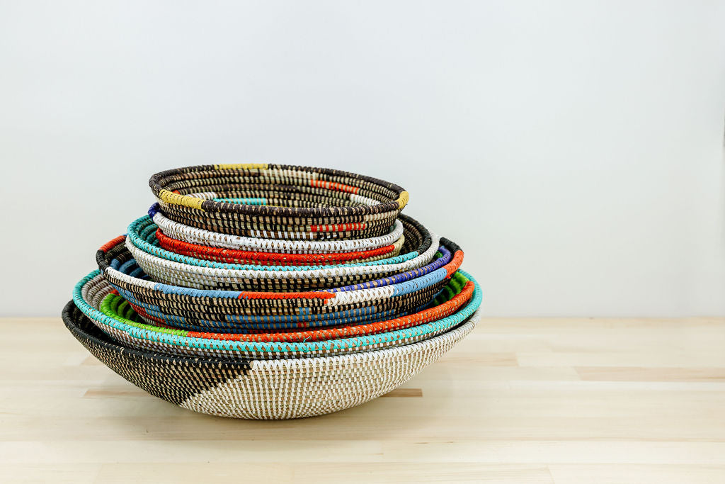 Stacked fair trade bowl baskets handcrafted from natural fibers, showcasing vibrant colors and traditional weaving techniques.