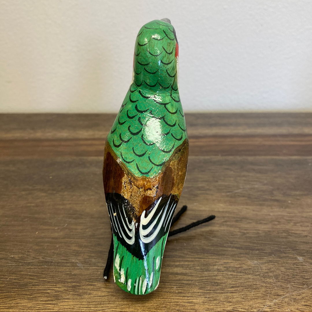 Back view of hand carved wooden hummingbird ornament, painted green with carved wing and tail details.