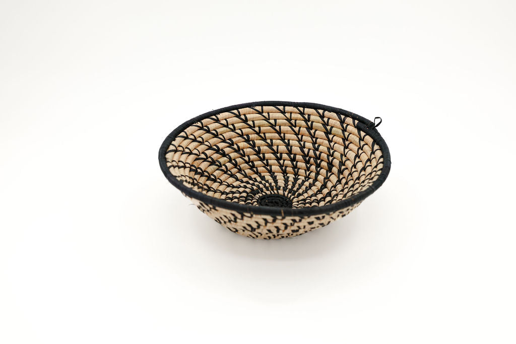 Handmade fair trade raffia wall basket in a black and natural color pattern, eco-friendly African home decor, perfect for boho styling and sustainable wall art.