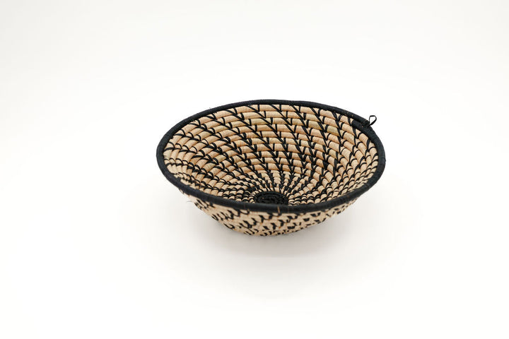 Handmade fair trade raffia wall basket in a black and natural color pattern, eco-friendly African home decor, perfect for boho styling and sustainable wall art.