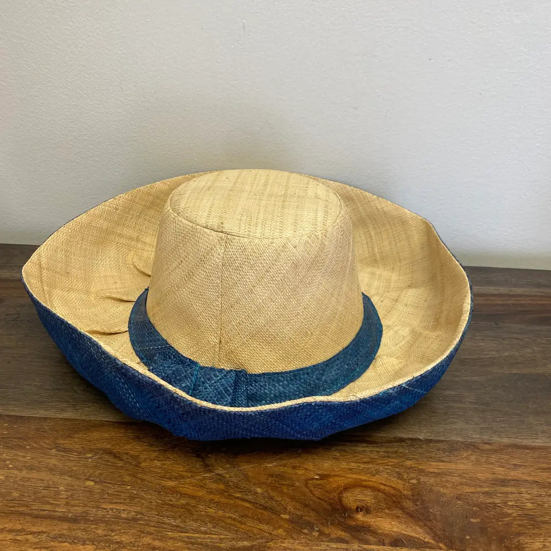 Beige straw hat with blue band on a wooden surface. Perfect for the beach and the park.