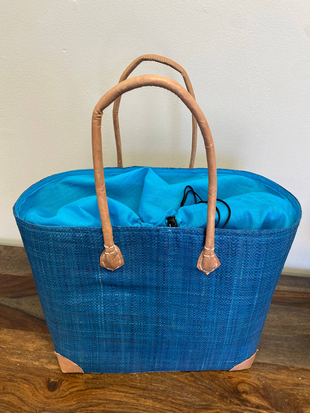 Ethically made raffia handbag with tan leather accents and inner pocket and drawstring top.

