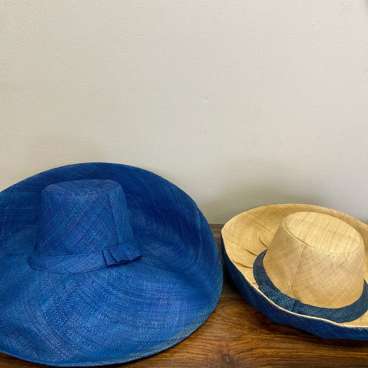 Blue and straw hats on a wooden surface with a white background. Great for the beach!