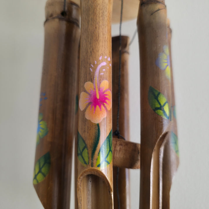 Close-up of vibrant flower designs on bamboo chimes, artisan-made garden décor.