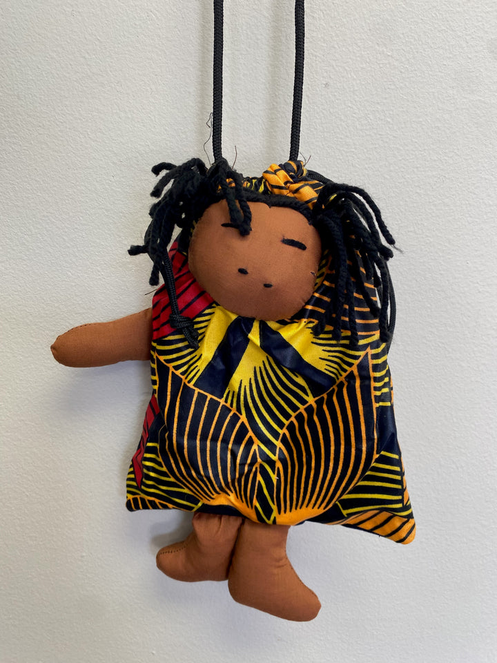 Up-cycled fabric bag with a sewn-in African doll, showcasing vibrant patterns and cultural design.