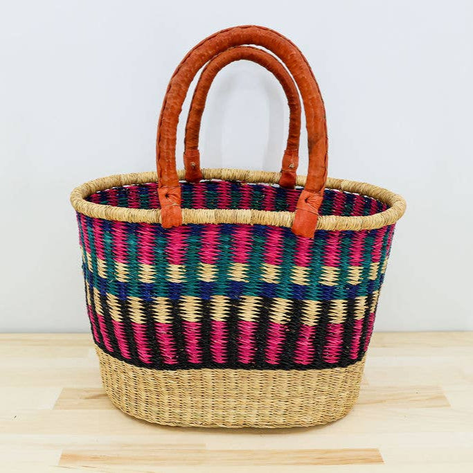 Colorful oval market basket with two leather handles.