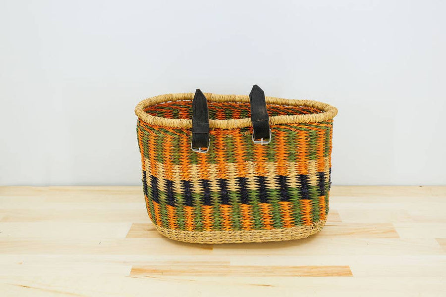 Fair trade handwoven bicycle basket with leather and brass buckle attachments, made from natural elephant grass.
