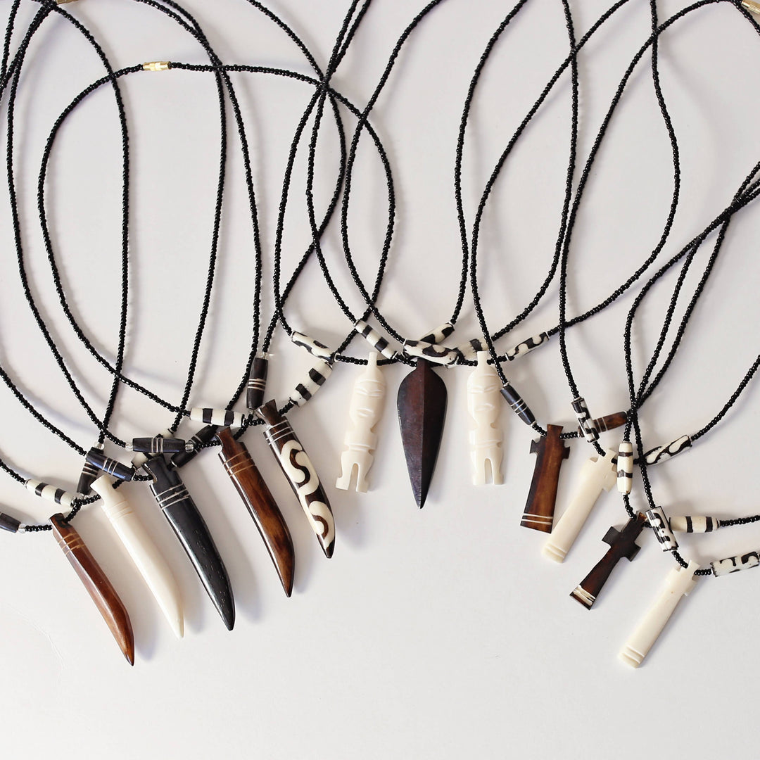 Fair trade hand-carved upcycled bone pendant necklace with glass beads and clasp closure.