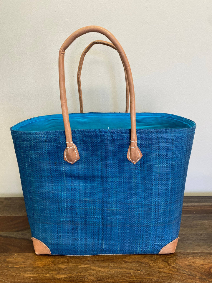 Handwoven tote bag made from palm leaf and raffia in bold blue solid color.