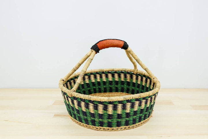 Fair trade round bread basket handwoven from elephant grass with leather handle, artisan-made in Ghana.