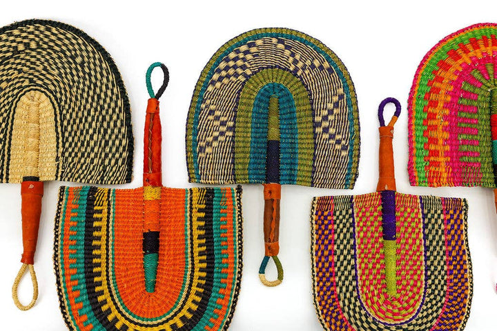 Fair trade Ghanaian fan resting on a table with vibrant colors and woven texture.