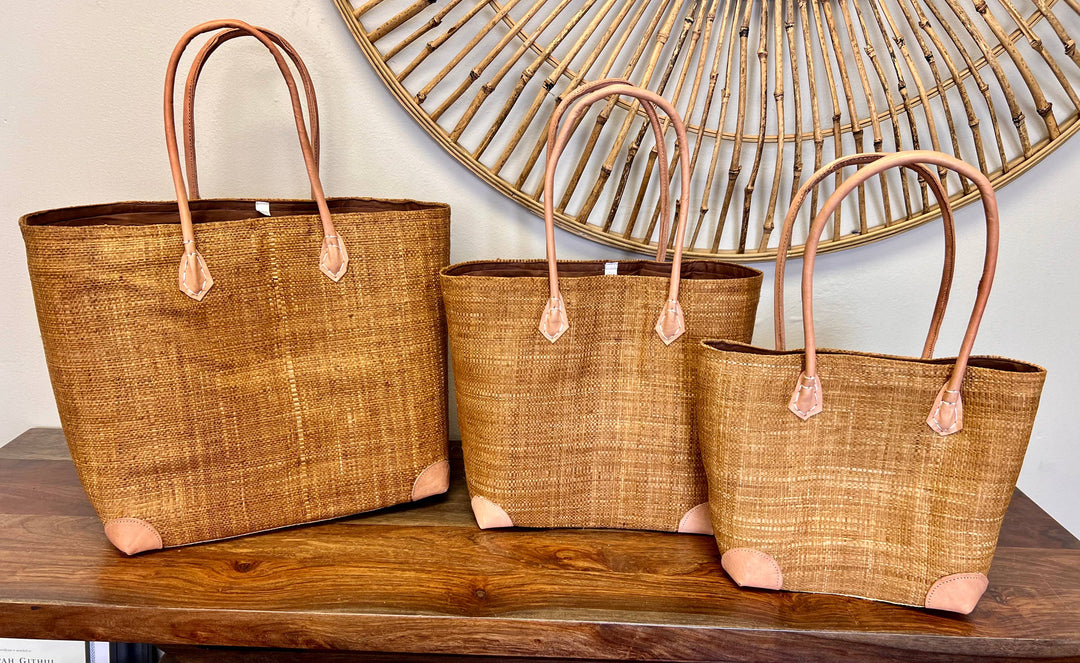 Fair trade solid color raffia handbag with leather handles and drawstring top.