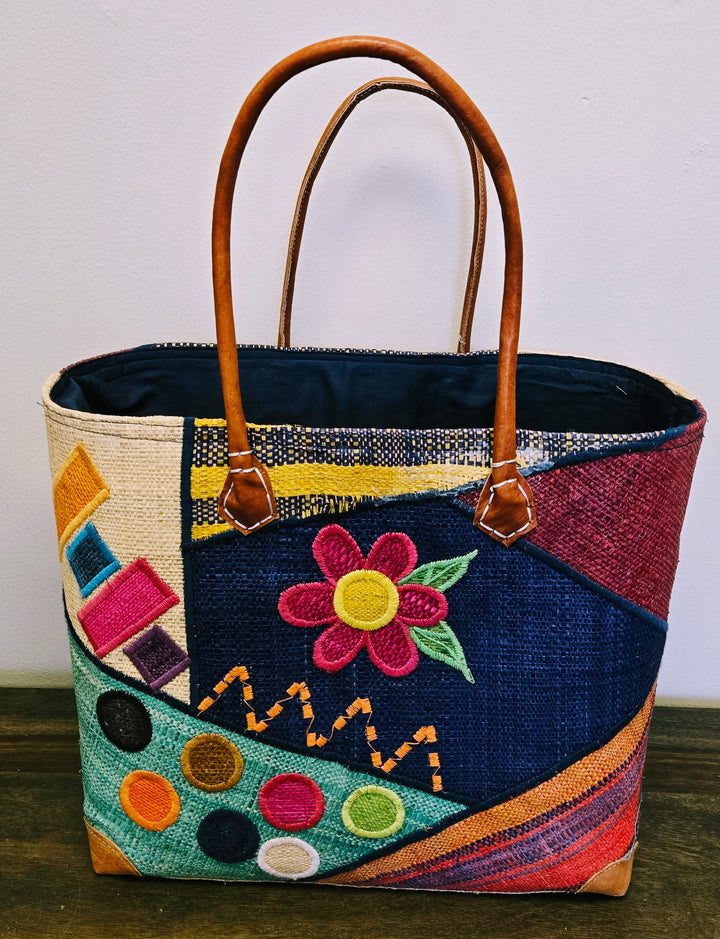 Fair trade flower motif tote bag with drawstring top and reinforced leather corners.
