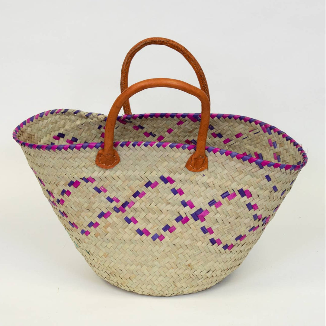 Durable natural palm basket with leather handles, suitable as a weekend bag or hamper.