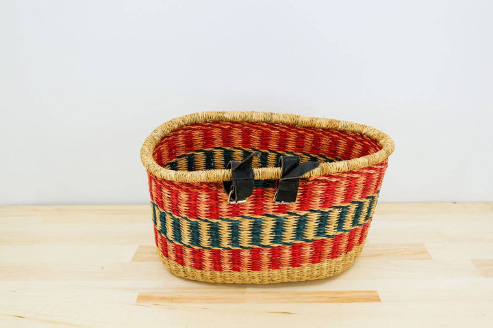 Eco-friendly fair trade handwoven bicycle basket with leather and brass buckle attachments for handlebars.