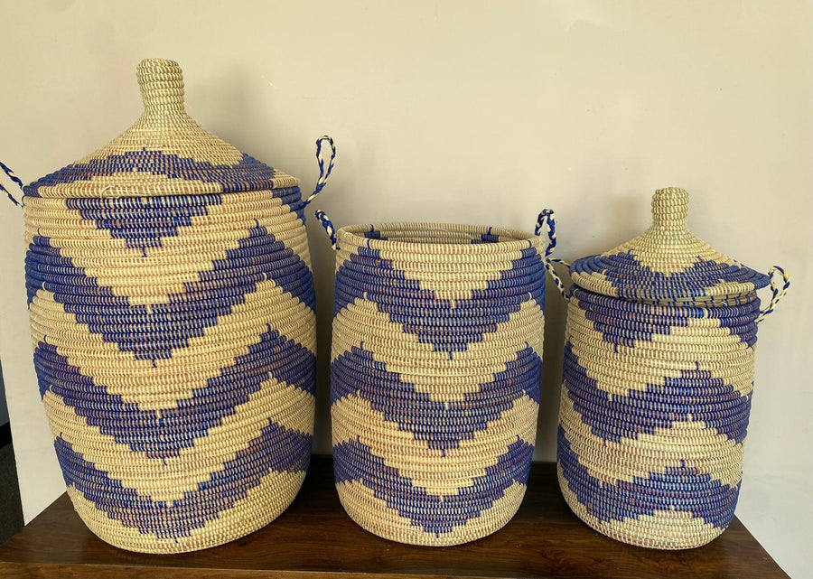 Three woven baskets with blue and beige patterns on a wooden surface.