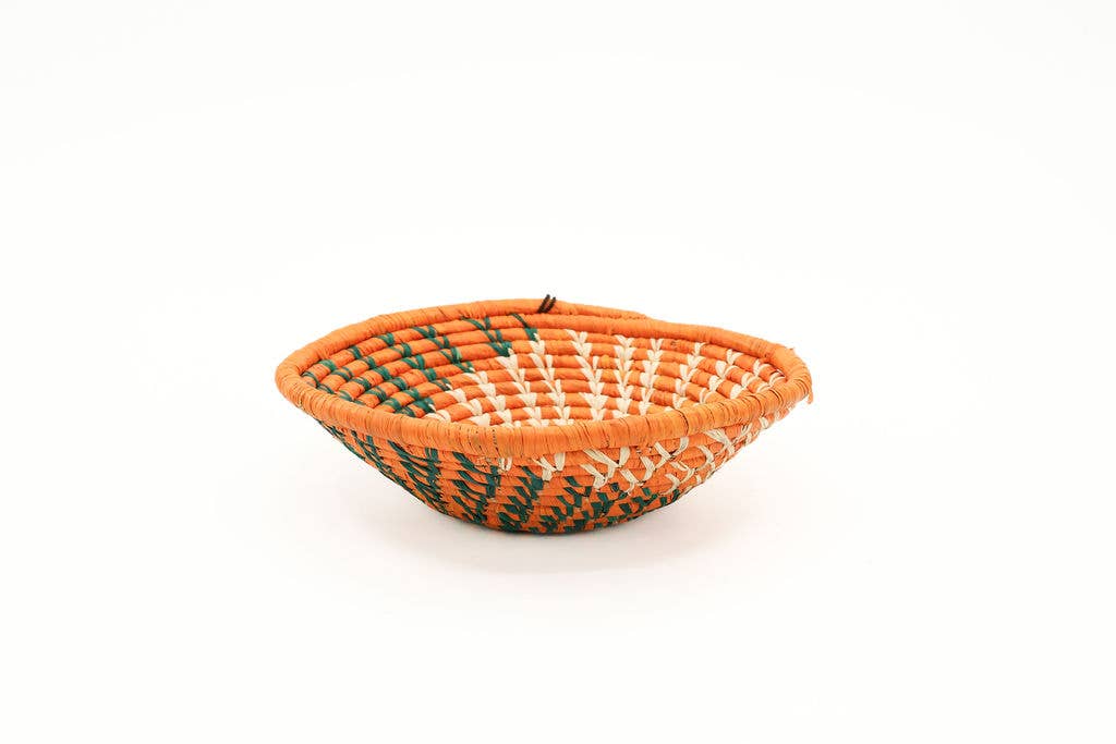 Orange handwoven raffia wall basket that showcases the beautiful fair trade home decor that is handmade in Kenya using sustainable natural fiber for eco-friendly and ethical styling.
