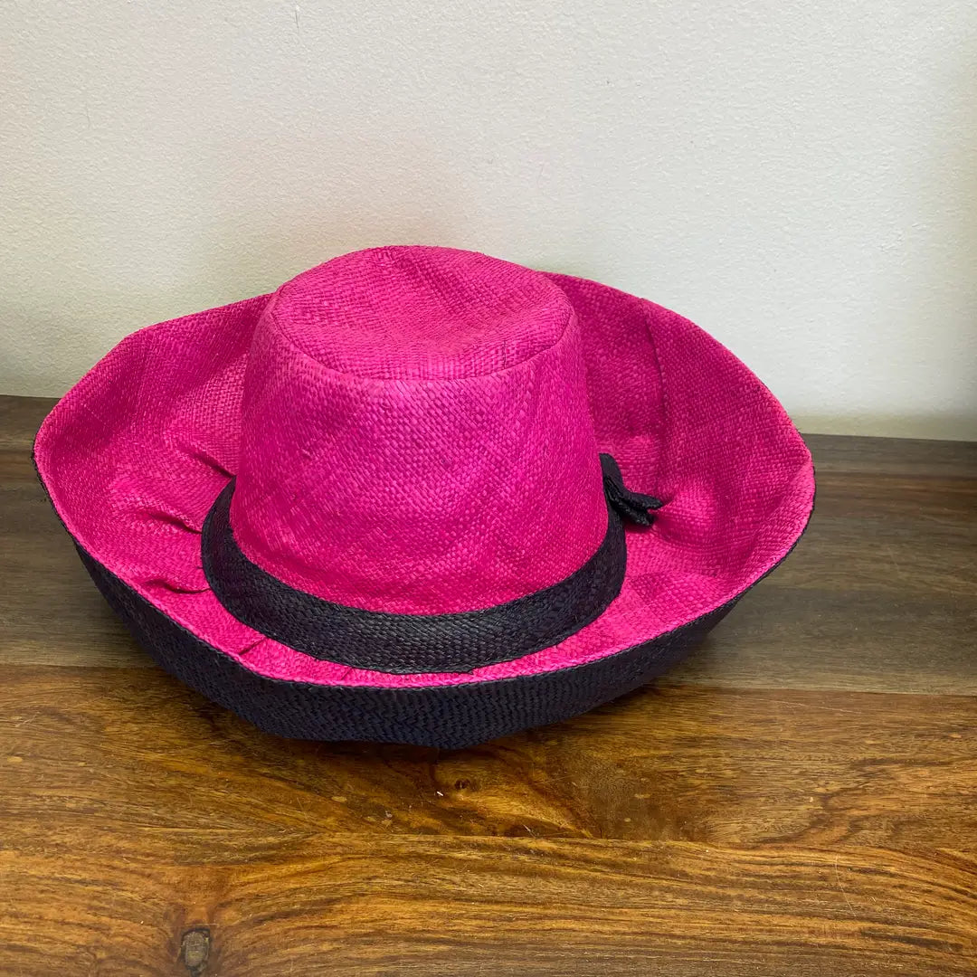 Pink straw hat with a black band on a wooden surface. Great for Easter and Church.