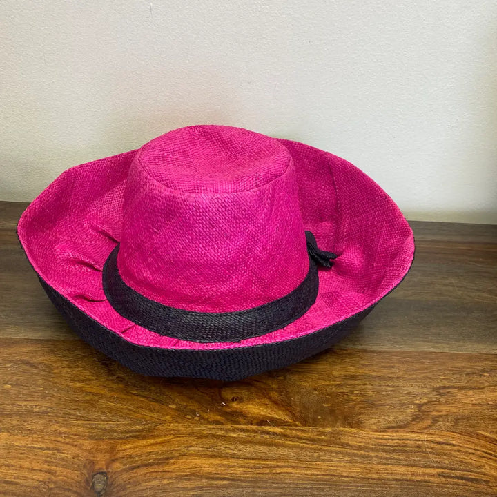 Pink straw hat with a black band on a wooden surface. Great for Easter and Church.