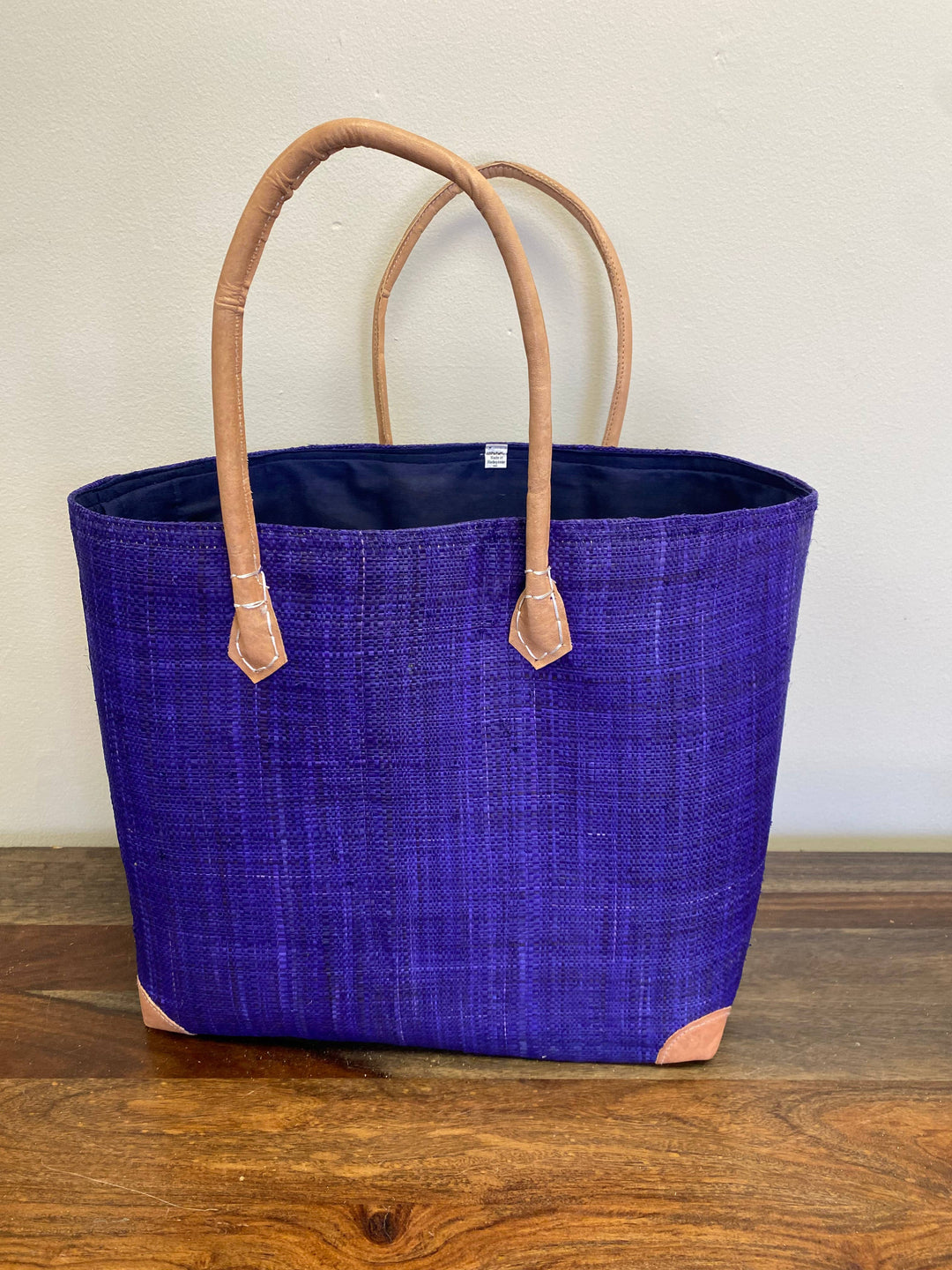 Artisan-crafted raffia purple tote with reinforced leather corners and fabric lining.