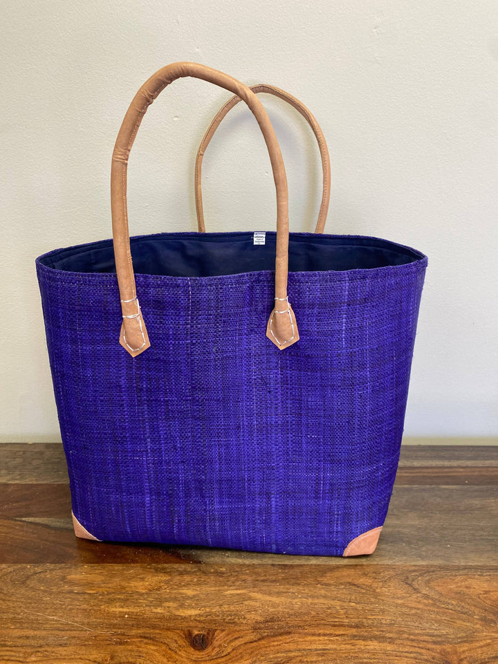 Artisan-crafted raffia purple tote with reinforced leather corners and fabric lining.