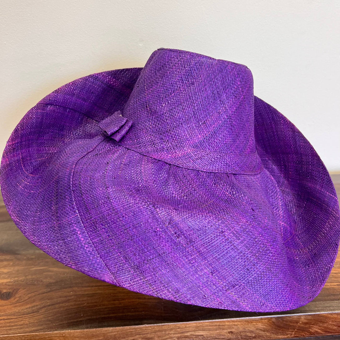 Natural raffia wide-brim hat displayed on table in sunlight.
