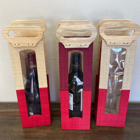 Three wooden wine gift boxes with red accents on a wooden surface.