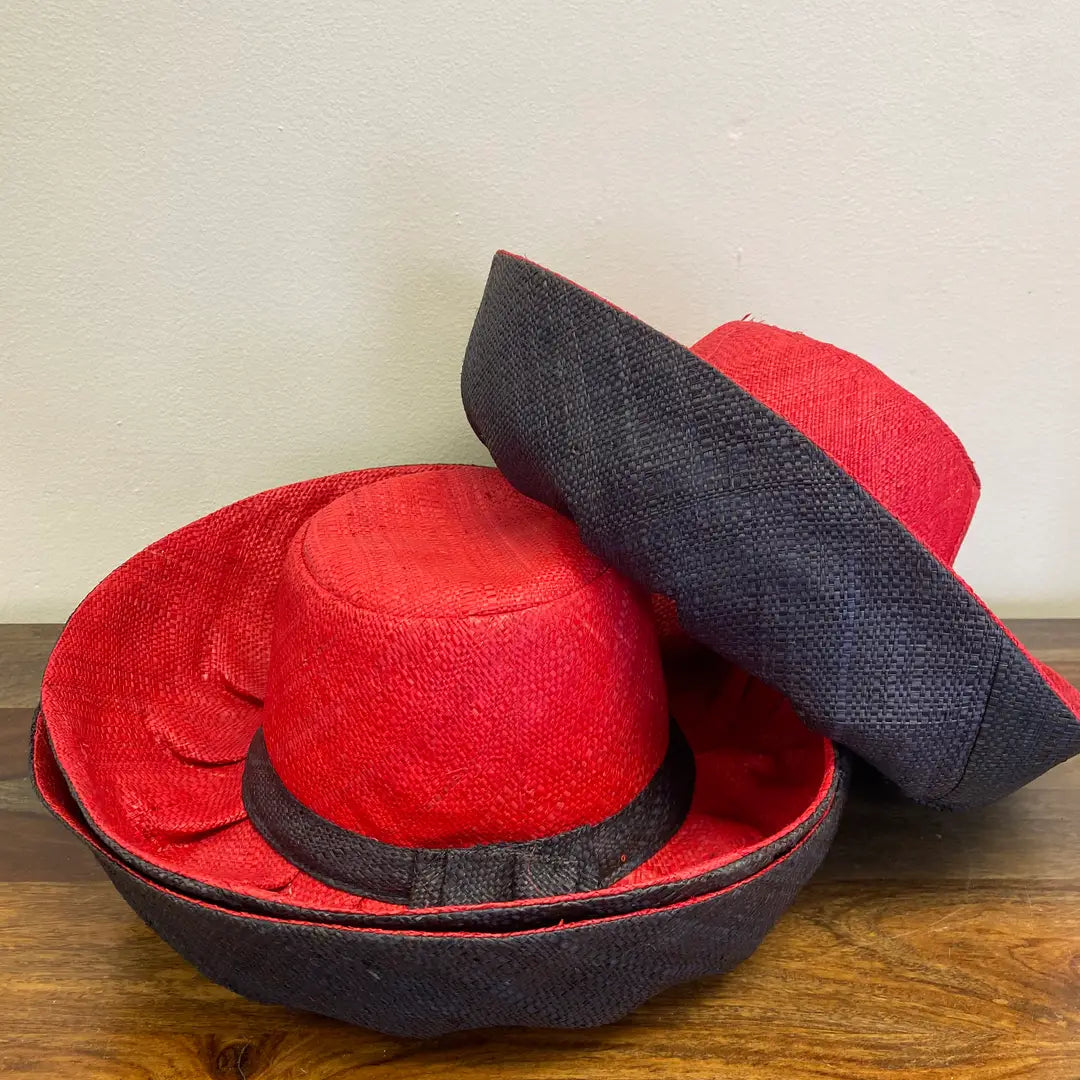 Red and black hats stacked on a wooden surface with a neutral background.