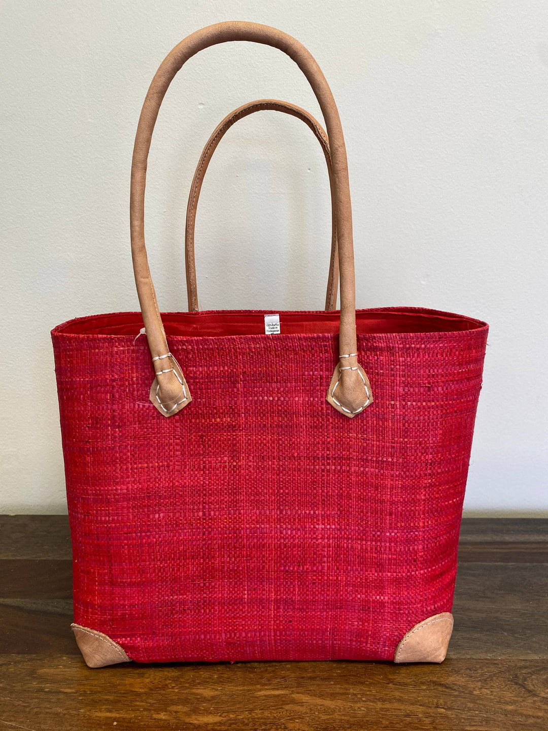 Sustainable raffia tote bag in vibrant red hue, handmade in Africa.