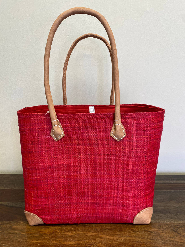 Sustainable raffia tote bag in vibrant red hue, handmade in Africa.