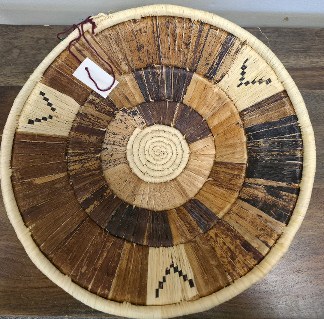 A neutral color round handwoven wall basket with banana leaf, made from raffia palm and banana leaves, intended for indoor use as wall art or storage.