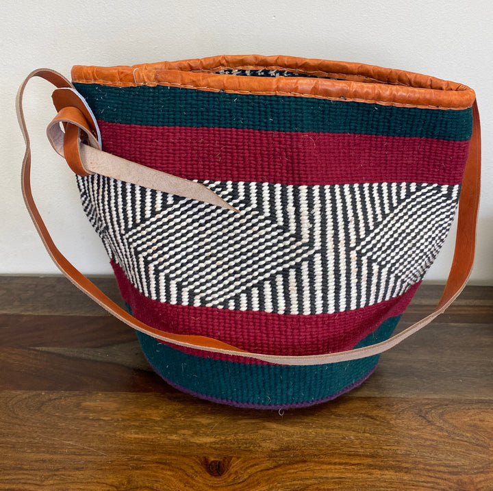 Woven tote basket with colorful patterns on a wooden surface.