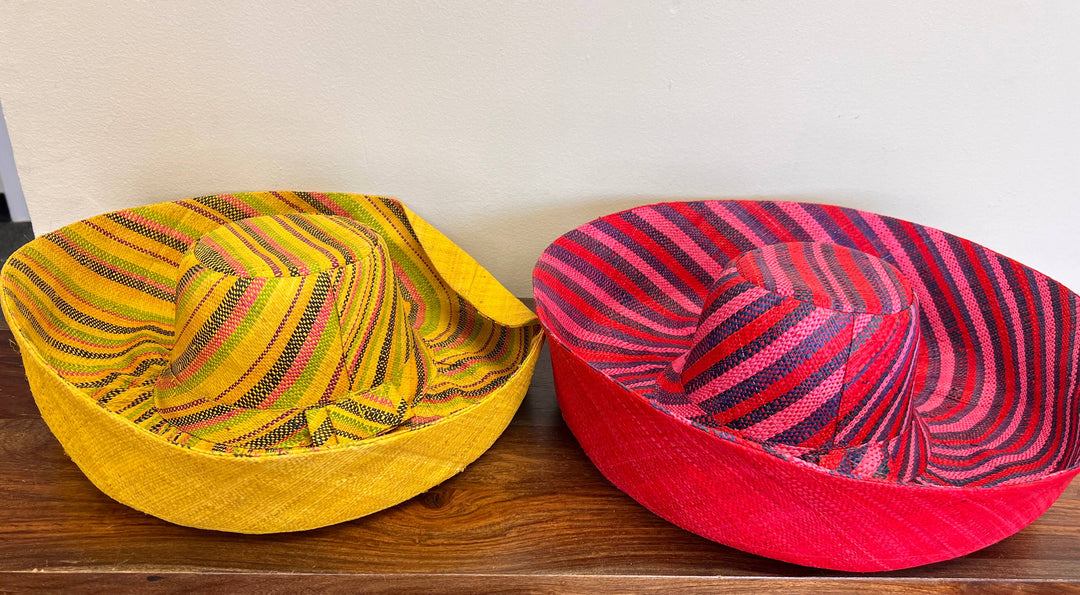 Wide-brim raffia hat resting on a woven basket backdrop.