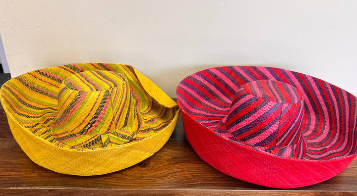 Wide-brim raffia hat resting on a woven basket backdrop.