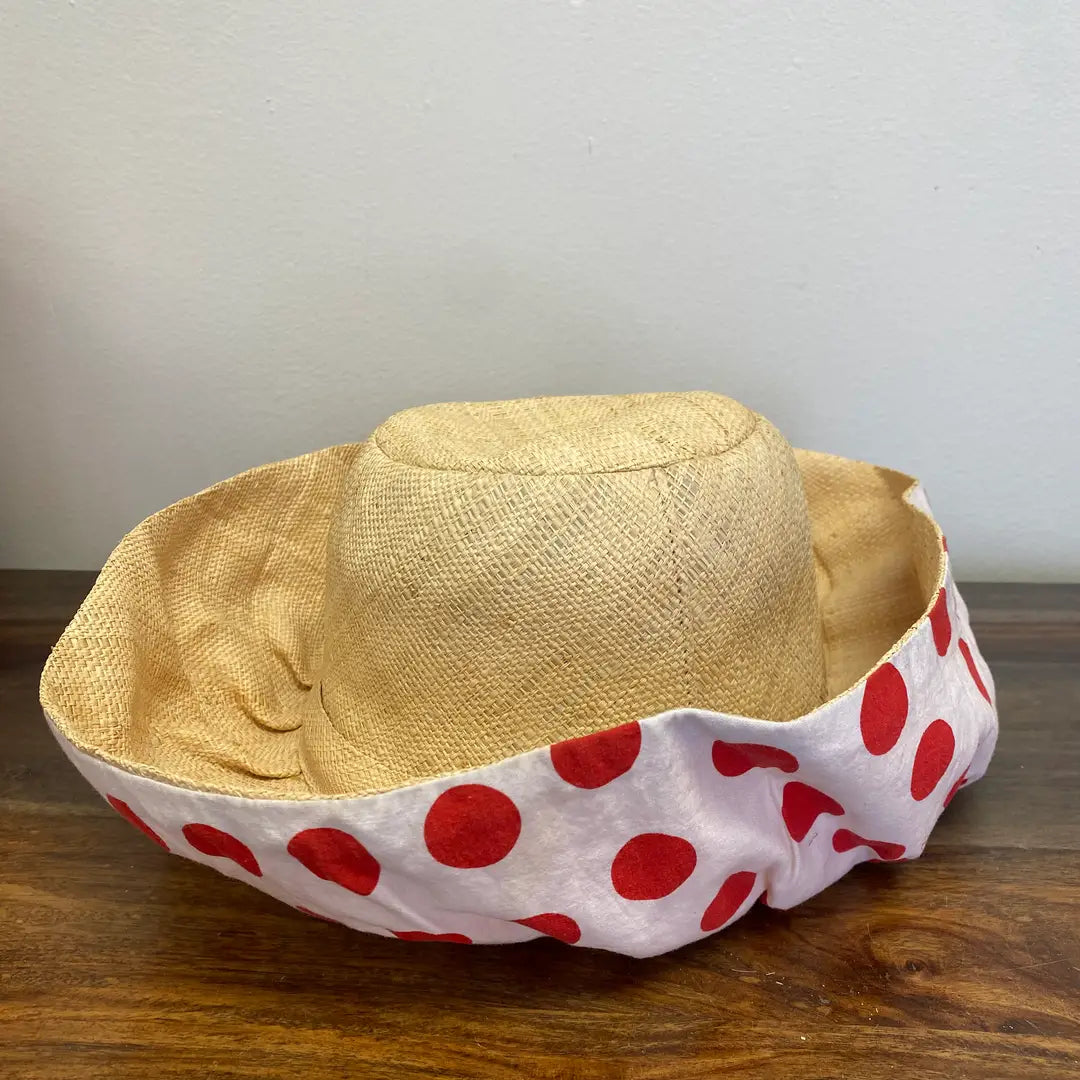 Straw hat with a red polka dot band on a wooden surface