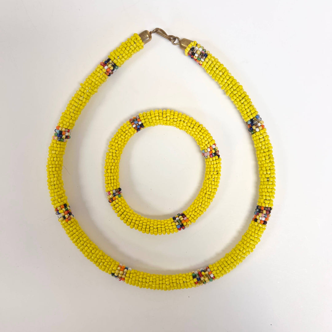 Close-up of wrapped yellow beadwork on plastic tube jewelry set.
