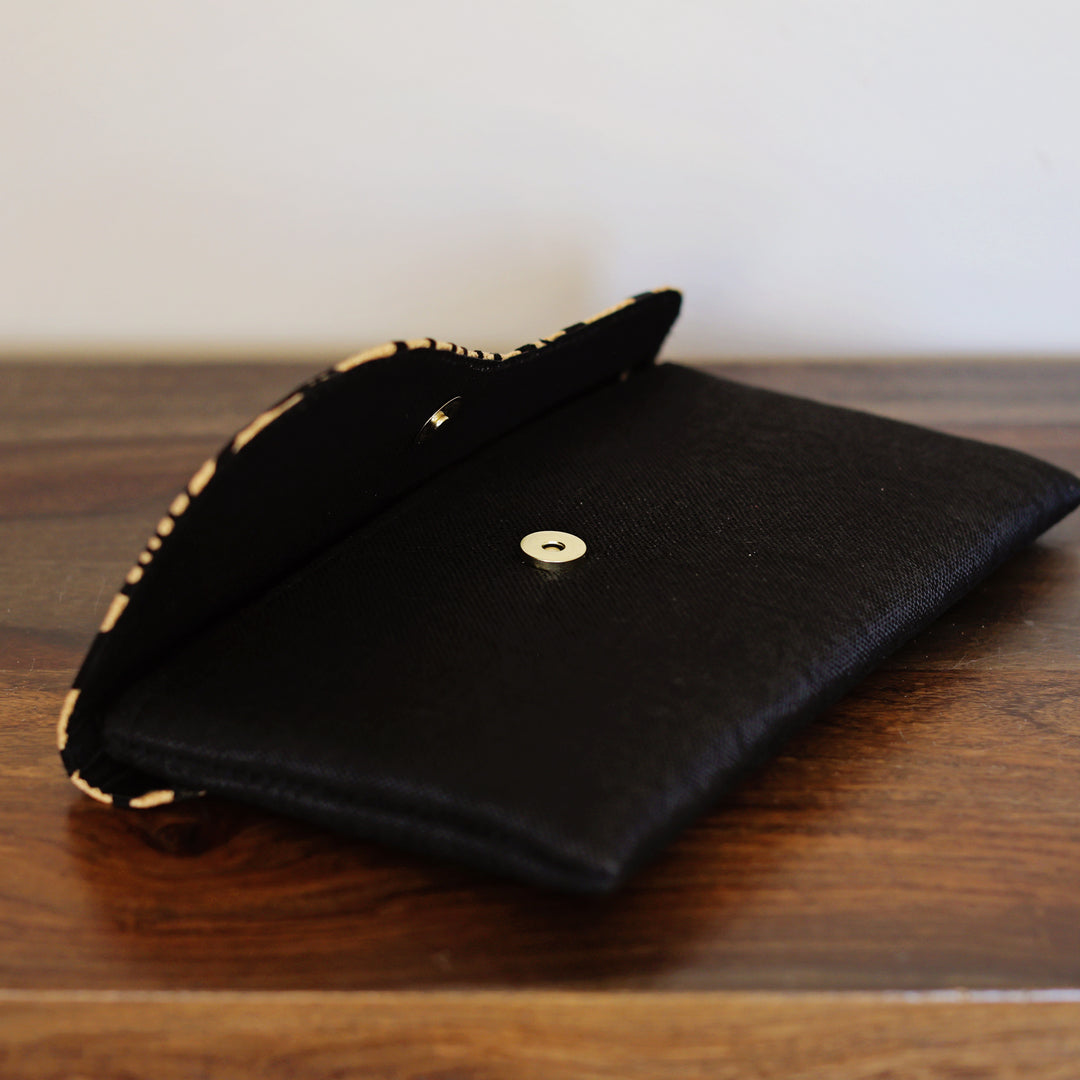Black base clutch purse, opened to show the snap detail.