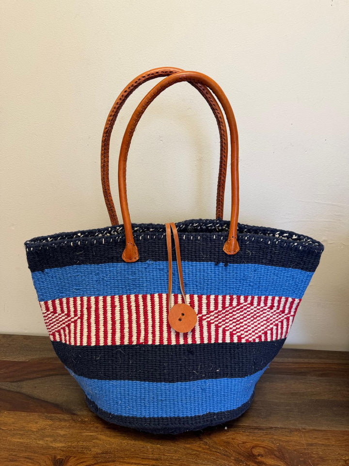 Woven handbag with blue, red, and white stripes, leather trim short handle and button front closure. Perfect for everyday.