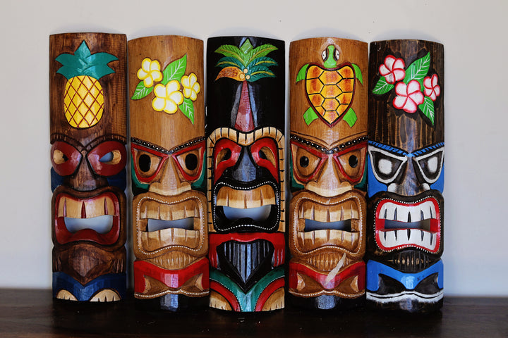 Assorted bamboo tiki masks displayed together as wall decor collection