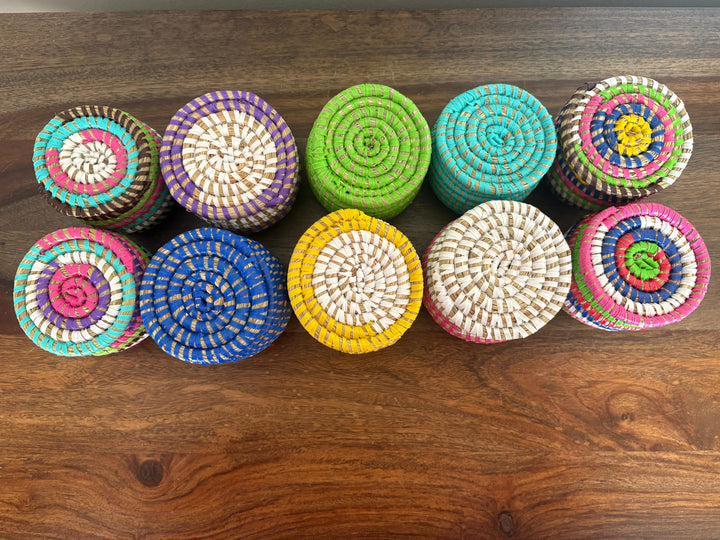 Assorted flat lidded mini sweetgrass baskets in colorful patterns.