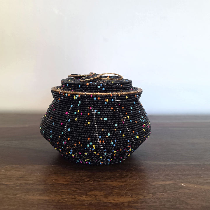 Black beaded handbag on a wooden surface with a neutral background