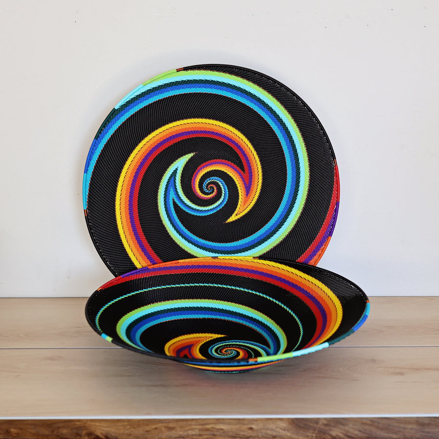 Black Rainbow Zulu Extra Large Shallow Basket handwoven in South Africa with colorful diagonal rainbow stripes on a black woven base.