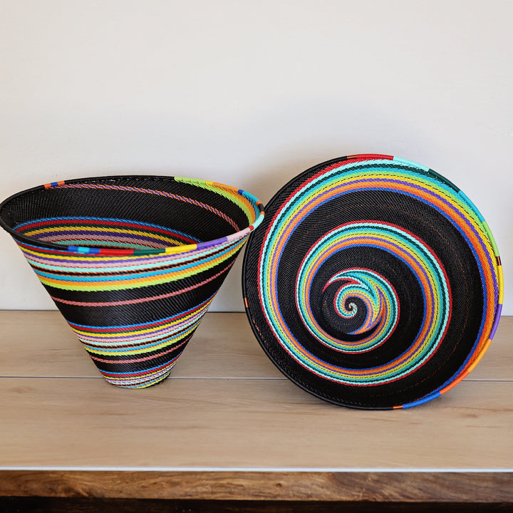 Black Rainbow Zulu Large Deep Funnel Bowl handwoven in South Africa with colorful diagonal rainbow stripes on a black woven base.