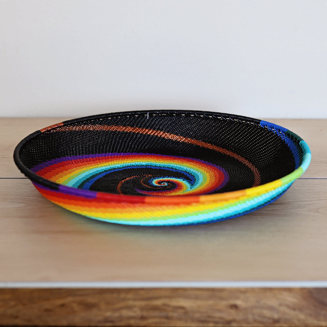 Black Rainbow Zulu Large Tray handwoven in South Africa with colorful diagonal rainbow stripes on a black woven base.