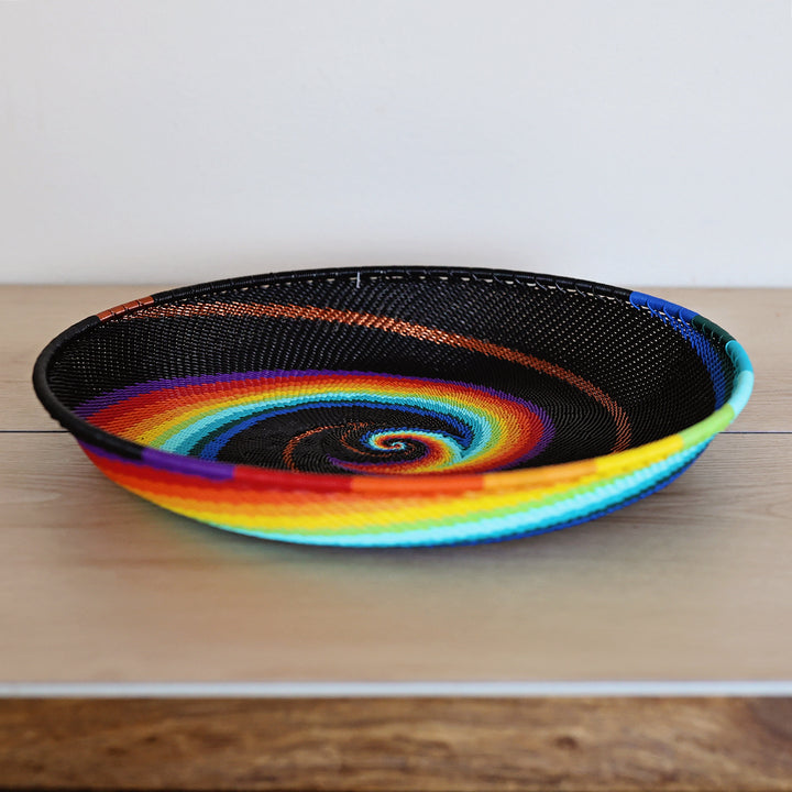 Black Rainbow Zulu Large Tray handwoven in South Africa with colorful diagonal rainbow stripes on a black woven base.