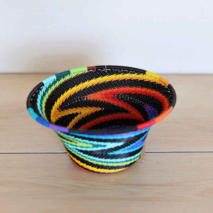 Black Rainbow Zulu Small Bowl handwoven in South Africa with colorful diagonal rainbow stripes on a black woven base.