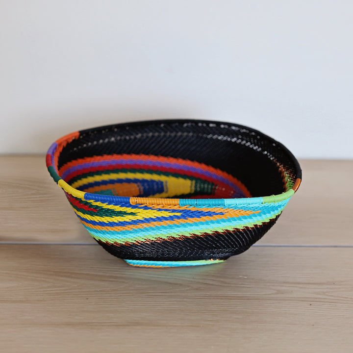 Black Rainbow Zulu Square Bowl handwoven in South Africa with colorful diagonal rainbow stripes on a black woven base.