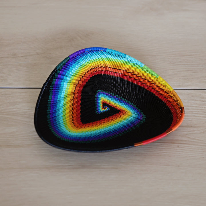 Black Rainbow Zulu Triangle Tray handwoven in South Africa with colorful diagonal rainbow stripes on a black woven base.