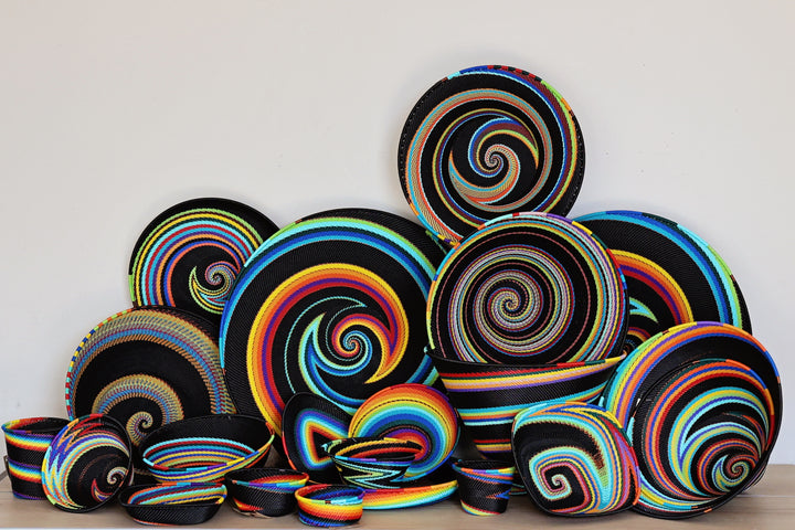 Collection of handwoven Black Rainbow Zulu Baskets featuring vibrant rainbow stripes and intricate African wire weaving.
