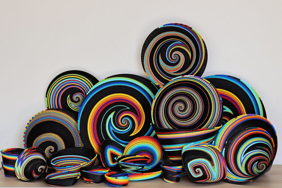 Collection of handwoven Black Rainbow Zulu Baskets featuring vibrant rainbow stripes and intricate African wire weaving.